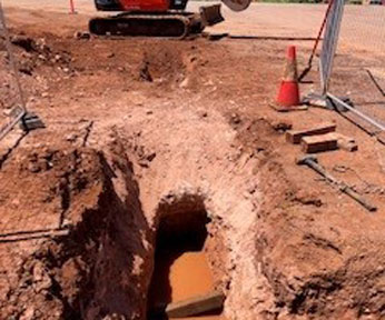 Ongoing horizontal rock drilling project along Stuart Highway, featuring a freshly excavated trench and visible drilling equipment